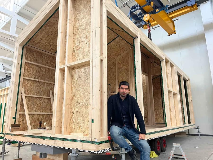 Nikolay, founder of Nextribe, sitting on the frame of a cabin under construction in the factory