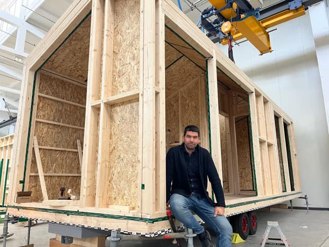 Nikolay, founder of Nextribe, sitting on the frame of a cabin under construction in the factory